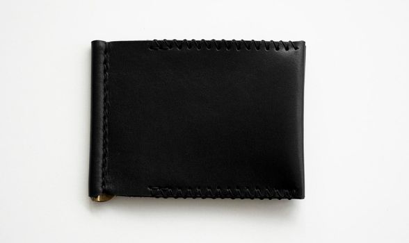 Black men's money clip handmade leather wallet for cards lies on a white table. Leather goods and accessory