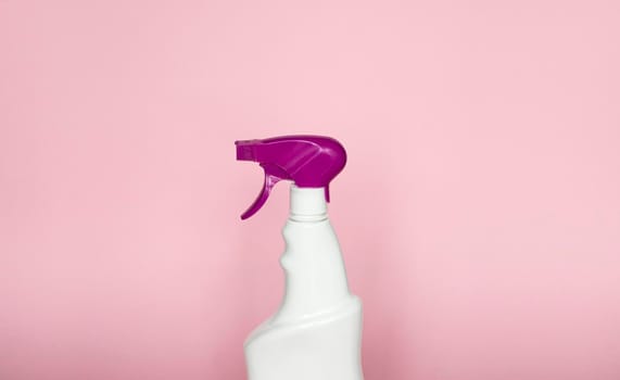 White blank plastic spray detergent bottle with a violet sprayer isolated on pink background. Packaging template mockup