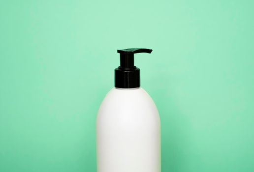 White plastic soap dispenser pump bottle isolated on green background. Skin care lotion. Bathing essential product. Shampoo bottle. Bath and body lotion. Fine liquid hand wash. Bathroom accessories