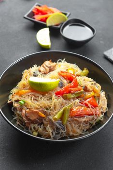 Glass noodle with vegetable in a black bowl on a grey background. Asian food Asian cuisine. Asian or Szechuan noodles