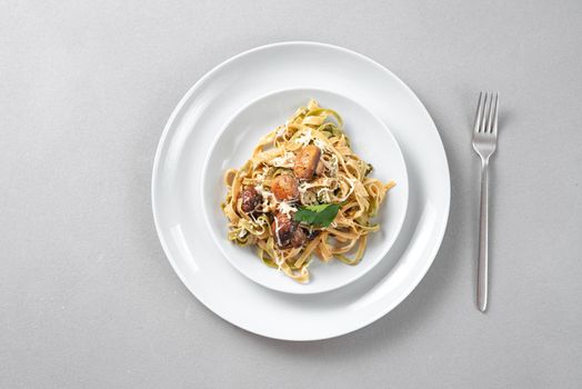 Linguine pasta with mushrooms, white cheese, spinach and garlic. Healthy eating. Vegetarian food. Diet. Italian pasta in a skillet with mushrooms and cream sauce on a white background. Top view.