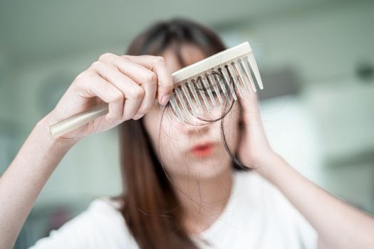 Asian woman have problem with long hair loss attach to comb brush.