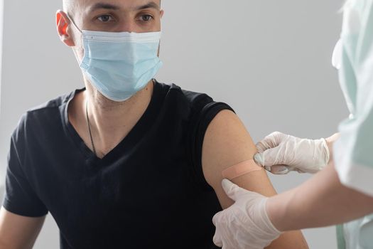 Doctor makes vaccination in the shoulder of patient in a hospital.