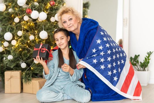 Family holding flag of USA at christmas. grandmother and granddaughter.