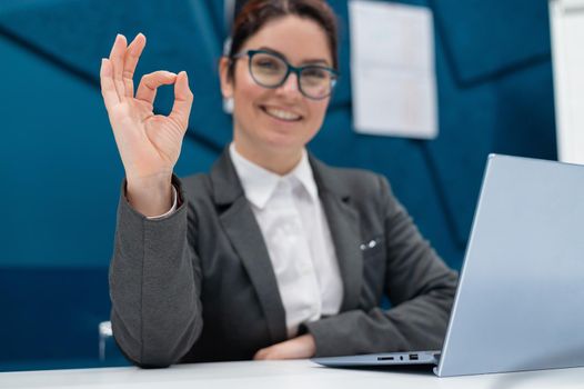 Business woman sitting at her desk and gesturing okay