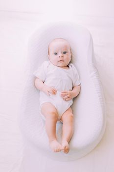 The baby is lying in a cocoon of copy space . The baby is 0-3 months old. A contented infant. An article about choosing a cocoon for newborns. An article about the benefits of cocoon. An article about colic . White background. High quality photo