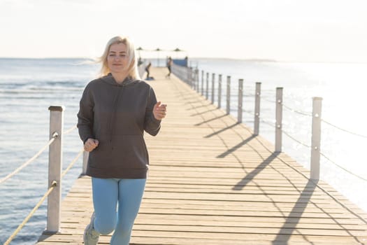 Young beautiful sportive girl training at sunrise over seaside