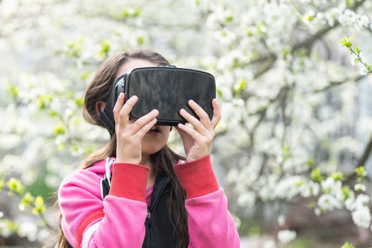Child with virtual reality headset sitting behind natrue outdoors at home