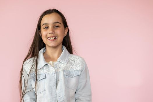 Portrait of pretty kid standing looking wearing trousers isolated over pink background.