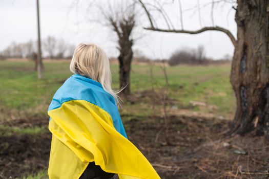 woman flag of ukraine near burnt tree.