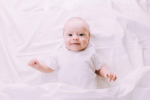 The baby is lying in his crib and looking at the camera . A happy child. Children's article. Copy Space