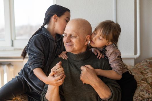 Ukrainian grandfather and two granddaughters hugging.