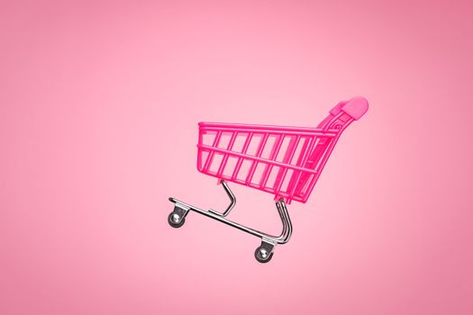 Empty trolley cart isolated pink background. Pink shopping trolley supermarket concept. Toy pink concept sales online shopping cart supermarket sales shopping symbol. Sale cart shop online marketplace