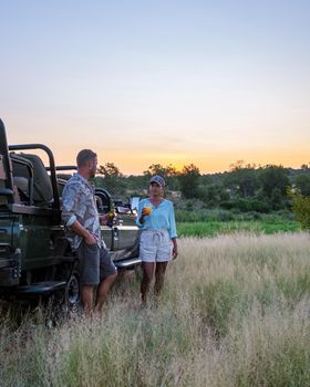 Asian women and European men on safari game drive in South Africa Kruger national park. a couple of men and women on safari. Tourist in a jeep looking sunset on safari