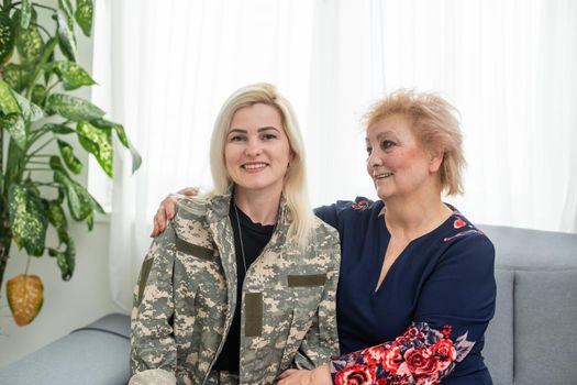 Soldier woman returning home to her family, embracing his mother, close up.