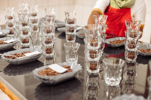 Close up of many water glasses and bowls with coffee particles for tasting on the table