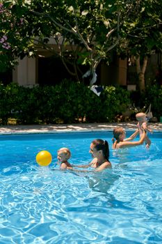 Moms with small children play with a ball in the pool. High quality photo