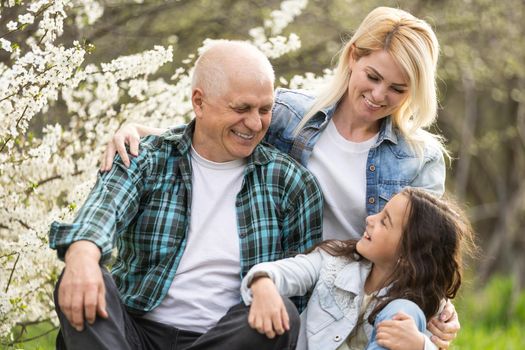 grandfather with granddaughter and daughter in spring, senior man in the yard.