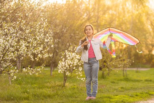 Happy child playing with colorful kite outdoors. Kid having fun in green spring field. Freedom and imagination concept.