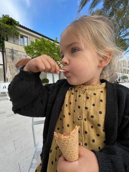 Little girl eats ice cream with a spatula from a waffle cup. High quality photo