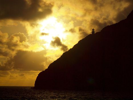 Sunsire over Historic Makapu'u Lighthouse on cliffside mountain top with pacific ocean below on Oahu, Hawaii.
