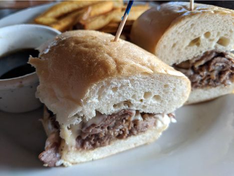 French dip sandwich with french fries.  In American cuisine, the French dip sandwich, also known as a beef dip, is a hot sandwich consisting of thinly sliced roast beef on a "French roll" or baguette. It is served topped with Swiss Cheese, onions, and a side of sauce, pickles, and that is, with beef juice from the cooking process.