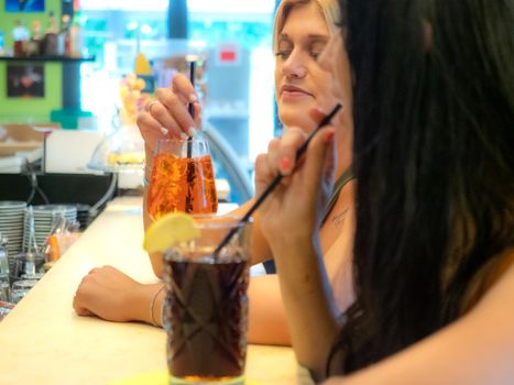 women friends drinking cocktails at the bar counter having good time