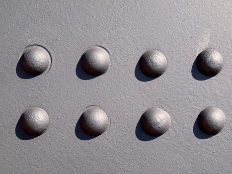 Detail of Black Metal wall with eight rivets making a pattern.