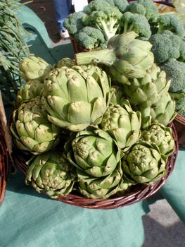 Pile of Artichoke and broccoli in baskets on display at a farmers market in San Francisco, CA.