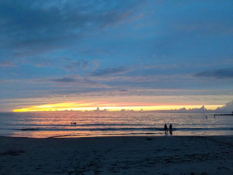 Sunset over ocean of Kaunaʻoa (Mauna Kea) Beach in the foreground on the Kohala Coast on the Big Island Hawaii. 
