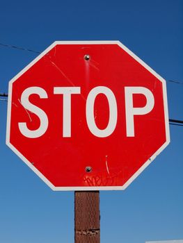 Red Stop Sign on wooden pole with power lines above.