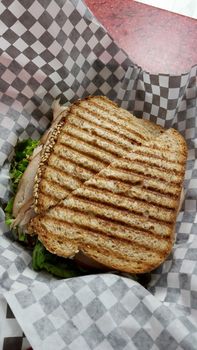 Grilled Turkey Sandwich featuring Turkey, Lettuce, Tomato on a piece of paper.