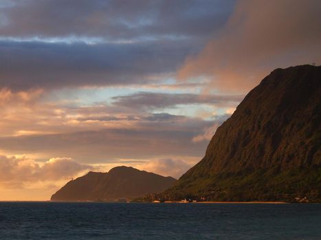 Waimanalo beach, bay, and Makapuu Point with Makapu'u Lighthouse visible on cliffside mountain on windward coast at dawn on Oahu, Hawaii.