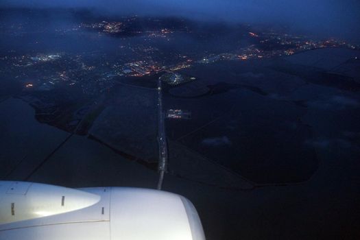 Aerial view Plane jet, salt evaporation ponds, bridge, and cities surrounding San Francisco Bay at dawn near San Jose, California, United States.