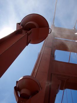 Upward perspective of Art Deco Lights, Tower and supporting cables on the Golden Gate Bridge in the fog.