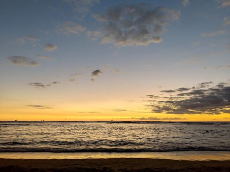 Dusk light reflecting on the Pacific ocean on the water with boats on the water off the beach of Waikiki on Oahu, Hawaii.