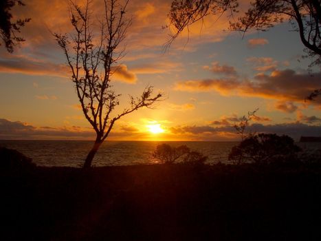 Sunrise on Waimanalo Beach on Oahu, Hawaii over ocean by Rabbit and Rock Island bursting through the clouds. 2012.