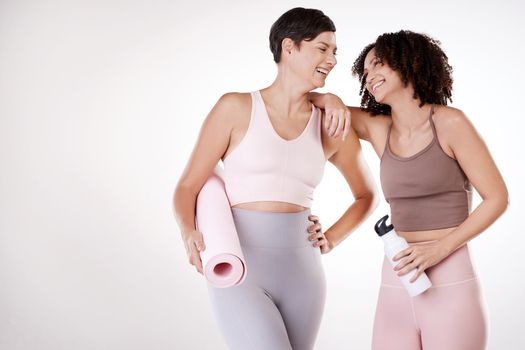 Mixing fun with fitness. two attractive young female athletes posing in studio against a grey background