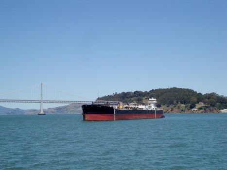 San Francisco - May 23, 2010: Cargo Boat in front of San Francisco Bay Bridge and Island on a clear day.