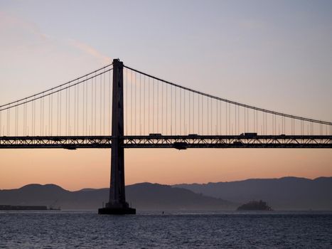 San Francisco side of Bay Bridge with Alcatraz in the distance at dawn.