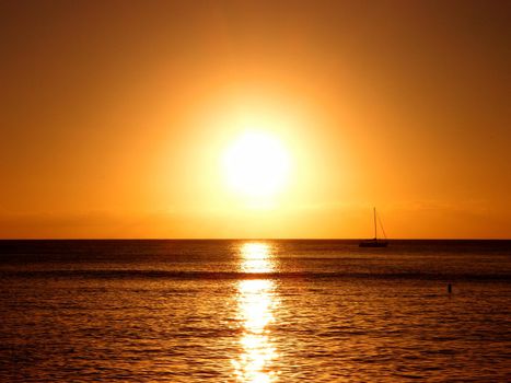 Sunset over the Pacific ocean reflecting on the water with boat off the coast of Oahu, Hawaii.