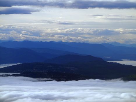 Aerial of Mountains peaking through the clouds in Washington State.