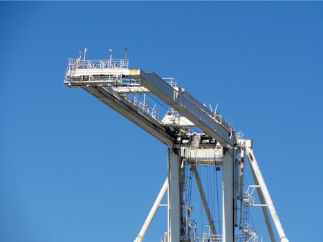 Lifting arm of Large crane with blue sky in Oakland Harbor, California.