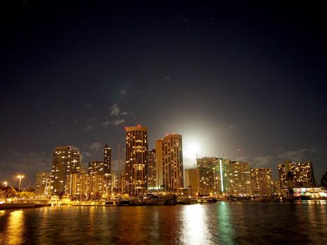 Full Large Moon raises over Waikiki hotels and Marina at Night on Oahu, Hawaii.