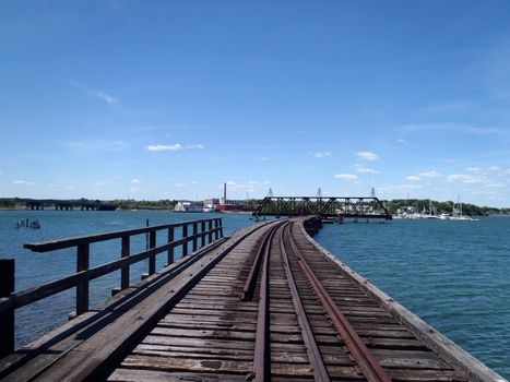 Railroad tracks on bridge across Back Cove in Portland, Maine during the day.