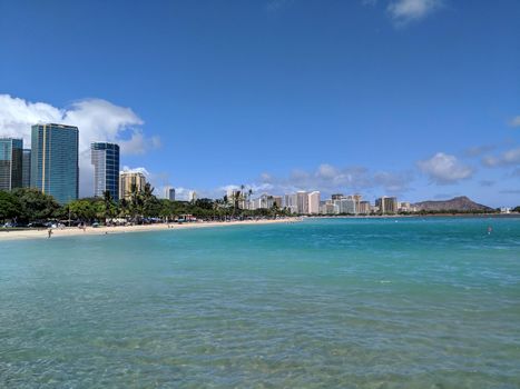 Waters of Ala Moana Beach Park with office building and condos in the background during a beautiful day on the island of Oahu, Hawaii. 