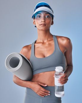 The most important ingredient in success is sweat. Studio shot of a fit young woman drinking bottled water against a grey background