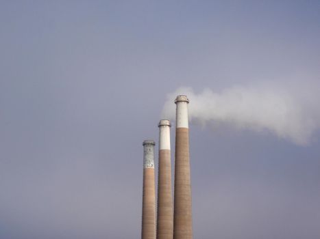 Three Smokestacks of the same size put pollution into the air in California.