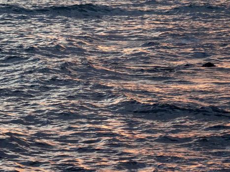 Little waves reflect twilight sunlight at dusk on Oahu, Hawaii.