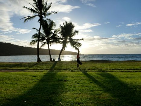 Man Handstands in grass field on Hanauma Bay beach at sunrise on Oahu, Hawaii.                    